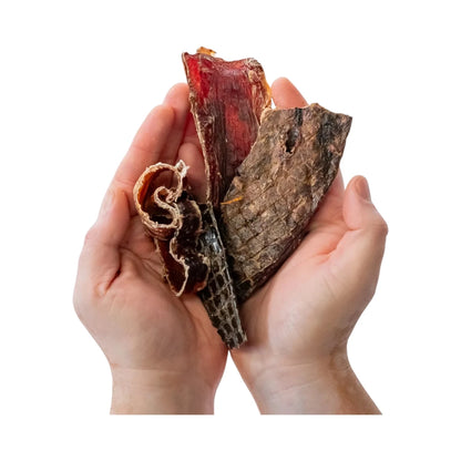 Manos sosteniendo piezas de Beef Mix: hígado, aritos de tráquea, esófago y pulmón de res deshidratados, mostrando variedad de texturas para masticación canina.
